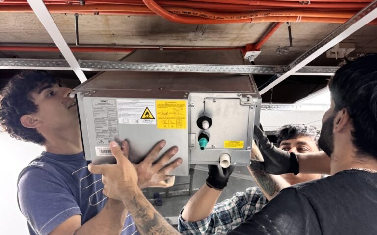 Técnicos instalando una unidad de aire acondicionado en el cielo